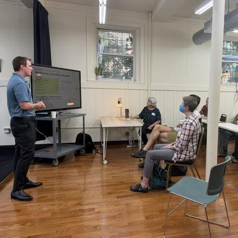 Aidan presenting a slide on unit prices to a seated group